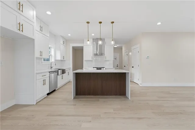 a large white kitchen with a large counter top stainless steel appliances and cabinets