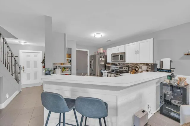 a kitchen with stainless steel appliances a refrigerator a sink dishwasher a stove with white cabinets and wooden floor