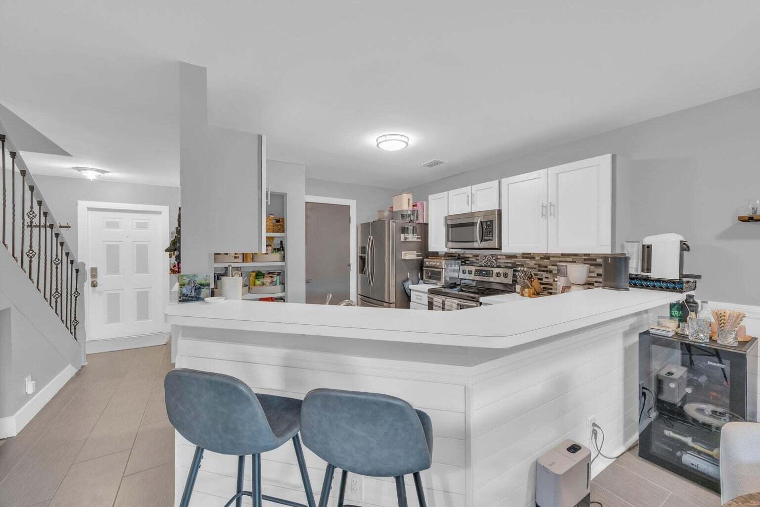 170 Timberwalk Trail Jupiter, FL 33458 - Photo 5 of 28 a kitchen with stainless steel appliances a refrigerator a sink dishwasher a stove with white cabinets and wooden floor