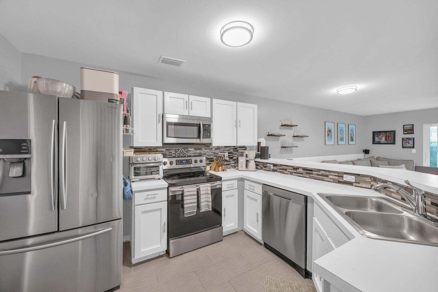 170 Timberwalk Trail Jupiter, FL 33458 - Photo 6 of 28 a kitchen with white cabinets and stainless steel appliances