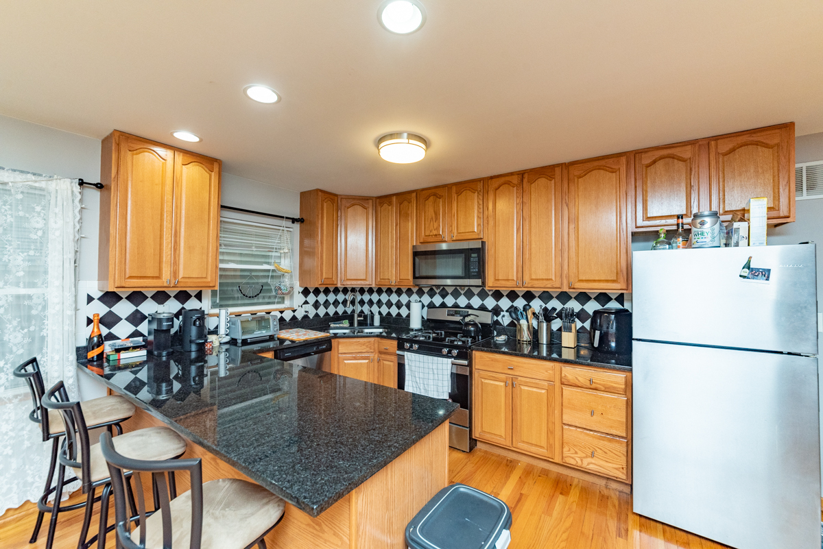 2932 North Ridgeway Avenue, Unit 1 Chicago, IL 60618 - Photo 3 of 25 a kitchen with granite countertop a refrigerator a stove a dining table and chairs with wooden floor