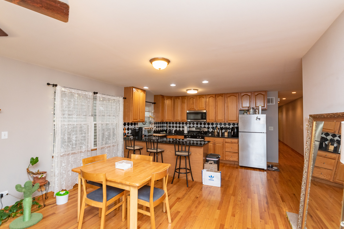 2932 North Ridgeway Avenue, Unit 1 Chicago, IL 60618 - Photo 4 of 25 a kitchen with stainless steel appliances kitchen island granite countertop a refrigerator a stove a dining table and chairs with wooden floor