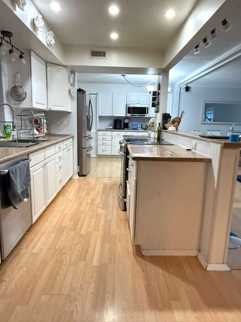 7024 Northwest 63rd Street Tamarac, FL 33321 - Photo 16 of 50 a large kitchen with stainless steel appliances lots of counter space and wooden floor
