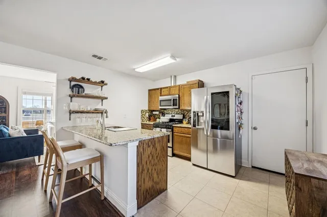 a kitchen with stainless steel appliances granite countertop a refrigerator and a stove top oven