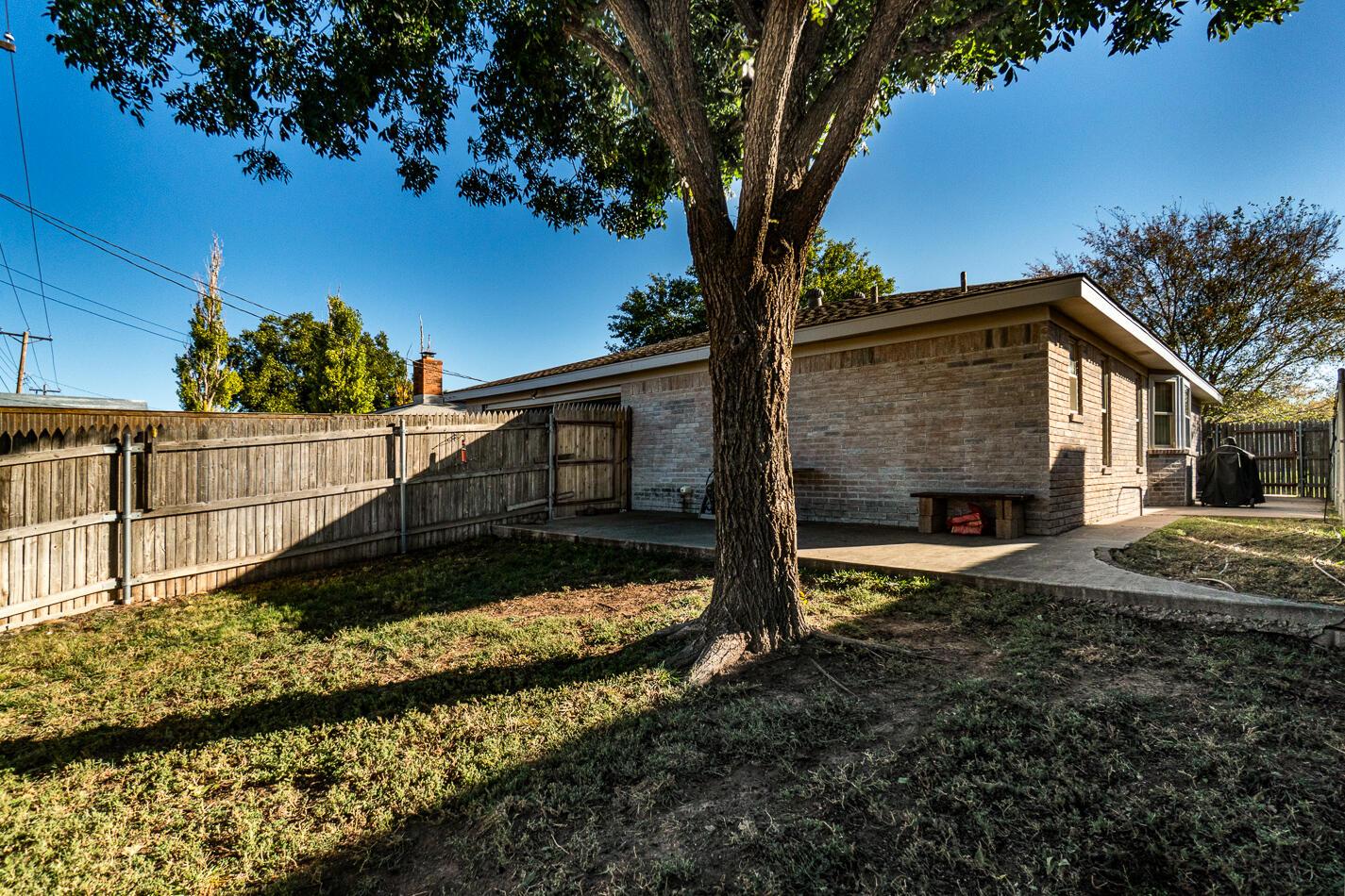 5702 South Milam Street Amarillo, TX 79110 - Photo 21 of 22 a view of a house with a small yard plants and a large tree