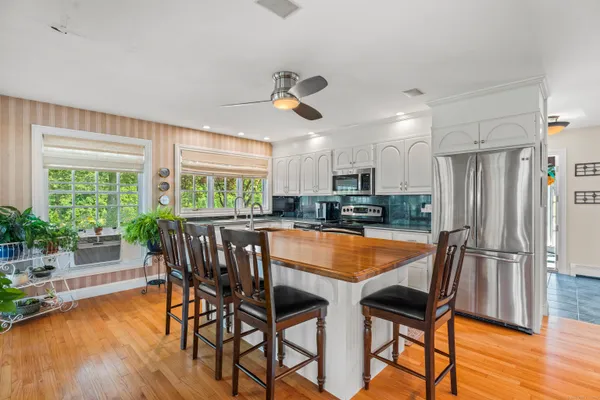 a kitchen with stainless steel appliances granite countertop dining table chairs and wooden floor
