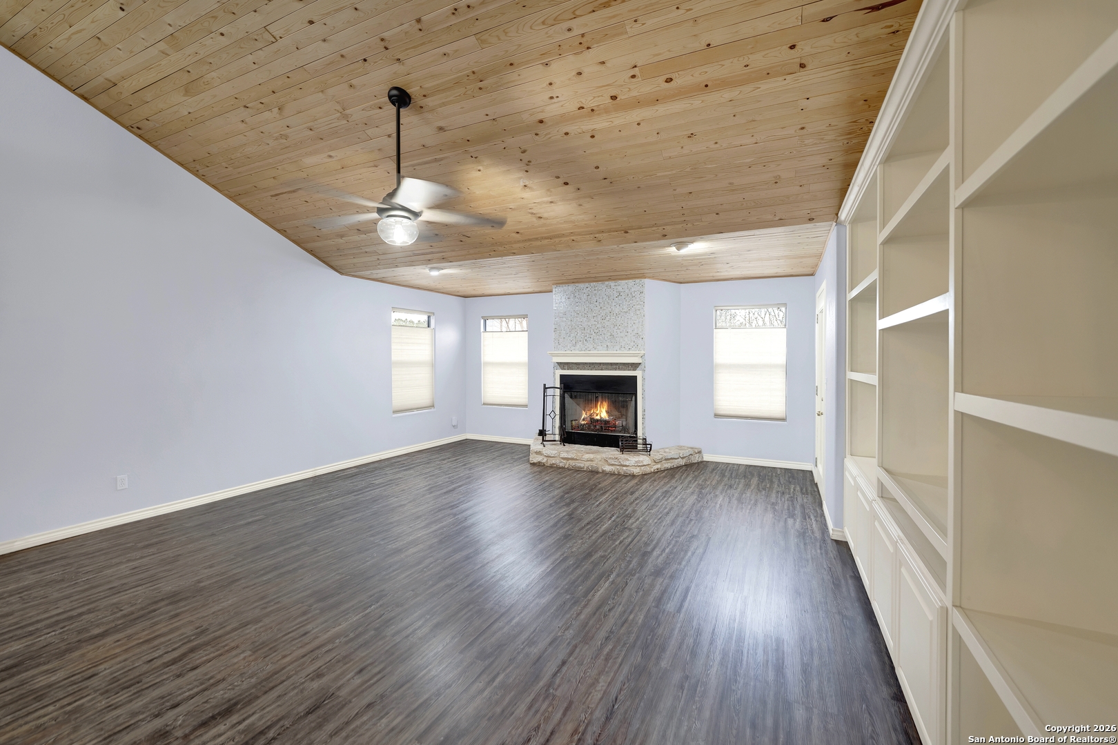 568 Firewheel Drive Bandera, TX 78003 - Photo 11 of 45 a view of an empty room with wooden floor fireplace and a window