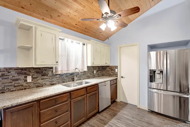 a kitchen with stainless steel appliances sink a refrigerator and white cabinets