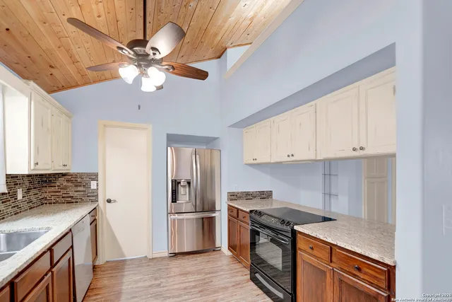 a kitchen with stainless steel appliances granite countertop a refrigerator a stove a sink and white cabinets