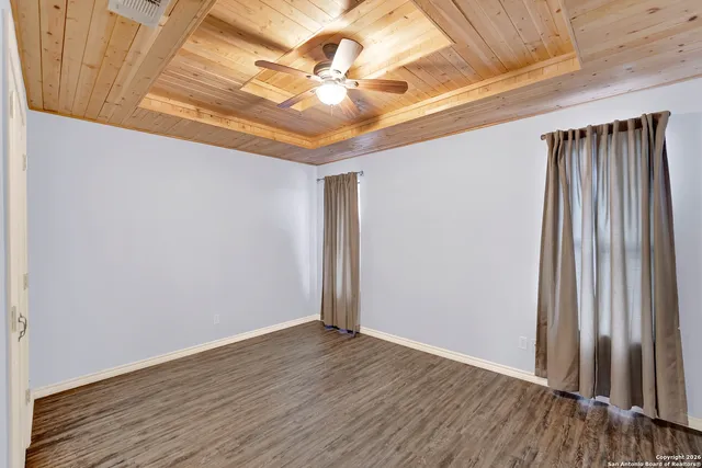 an empty room with wooden floor fan and windows