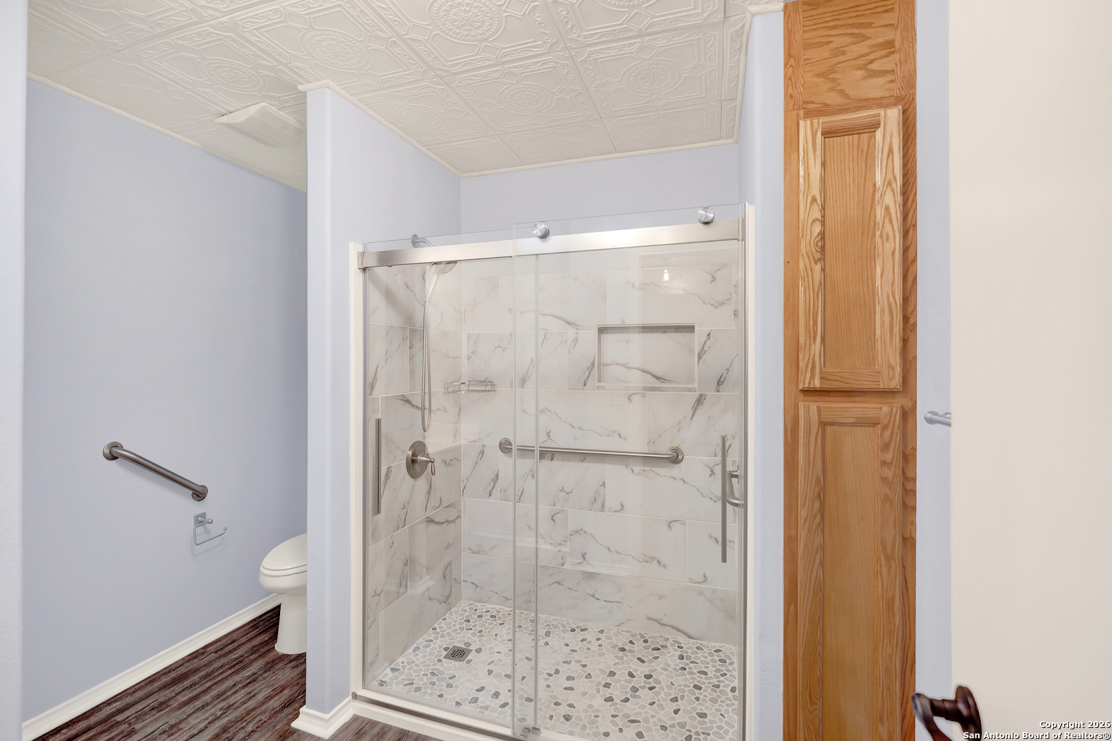 568 Firewheel Drive Bandera, TX 78003 - Photo 32 of 45 a bathroom with a glass shower door