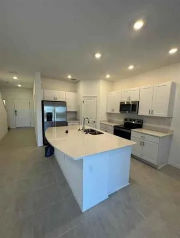 a large kitchen with kitchen island a sink a stove and a refrigerator