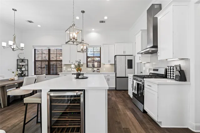 a large kitchen with kitchen island a stove a sink a refrigerator and a dining table with wooden floor