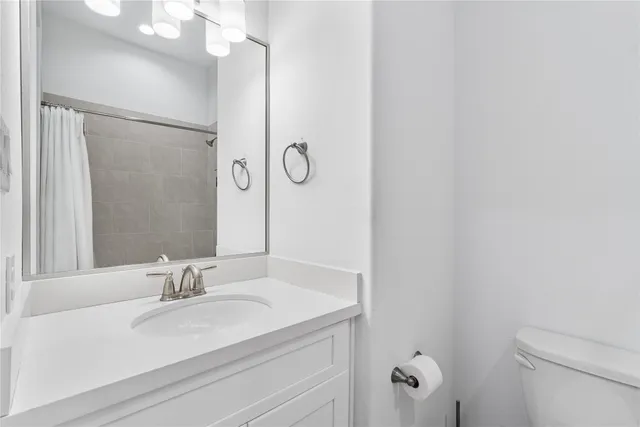a bathroom with a granite countertop sink toilet and a mirror