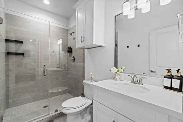 a bathroom with a granite countertop sink a toilet and shower
