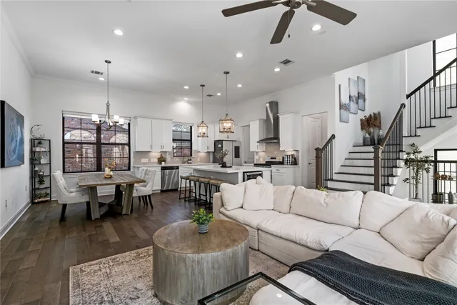 a living room with furniture kitchen view and a wooden floor