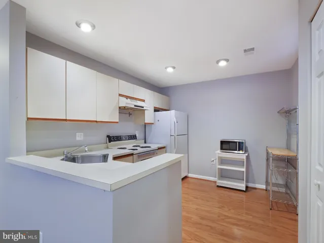 a kitchen with a sink a stove a microwave and white cabinets