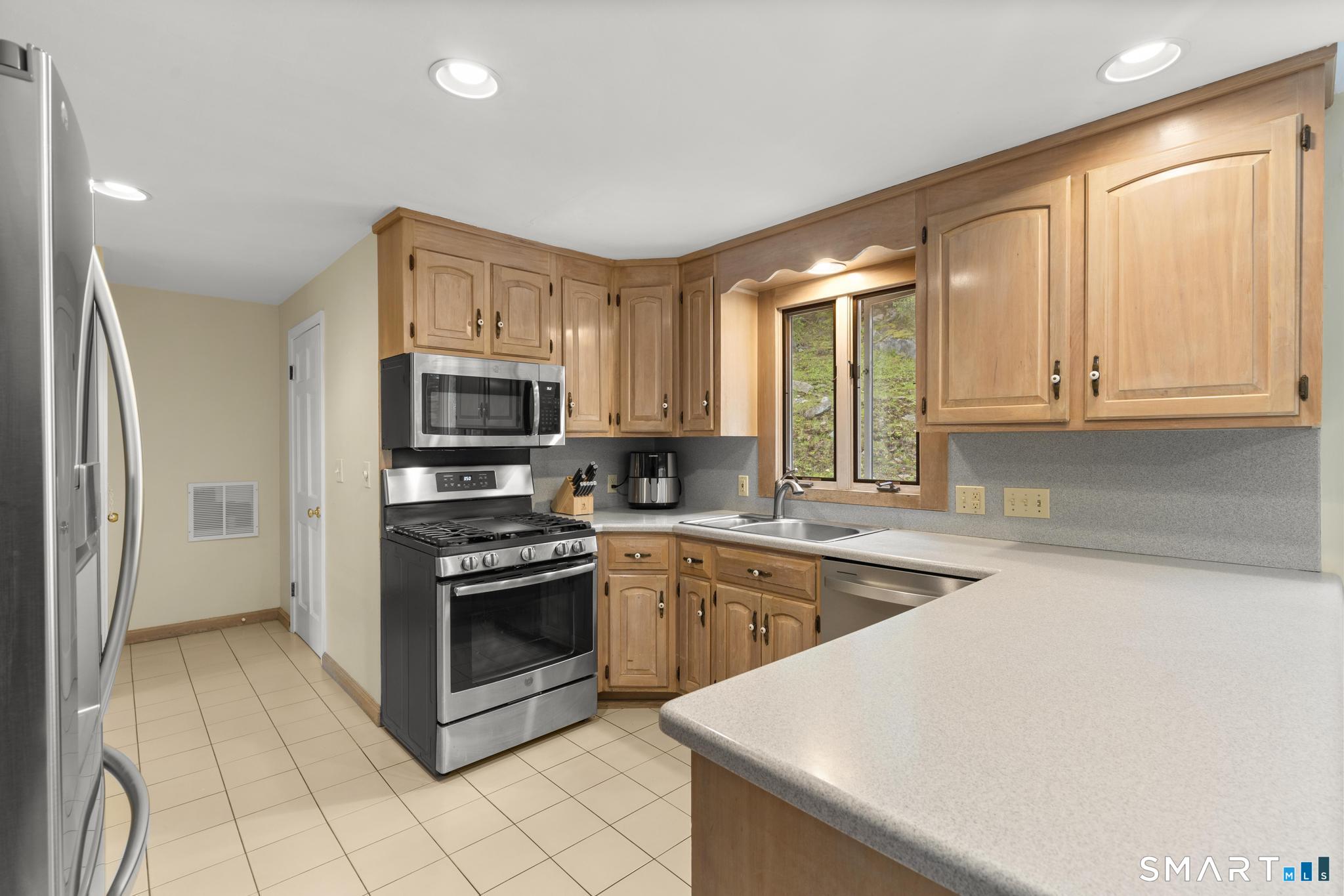 832 Quarter Mile Road Orange, CT 06477 - Photo 18 of 39 a kitchen with stainless steel appliances granite countertop a stove a sink and a microwave