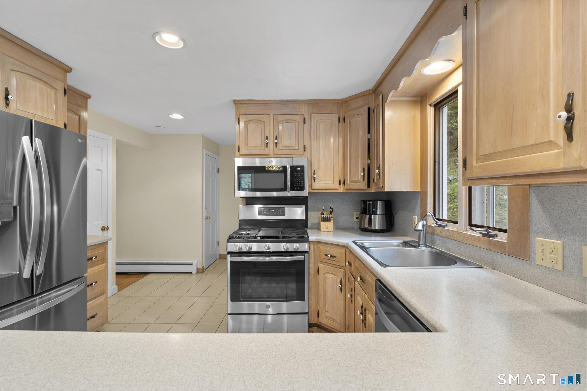 832 Quarter Mile Road Orange, CT 06477 - Photo 19 of 39 a kitchen with stainless steel appliances granite countertop a refrigerator a stove and a sink with wooden floors