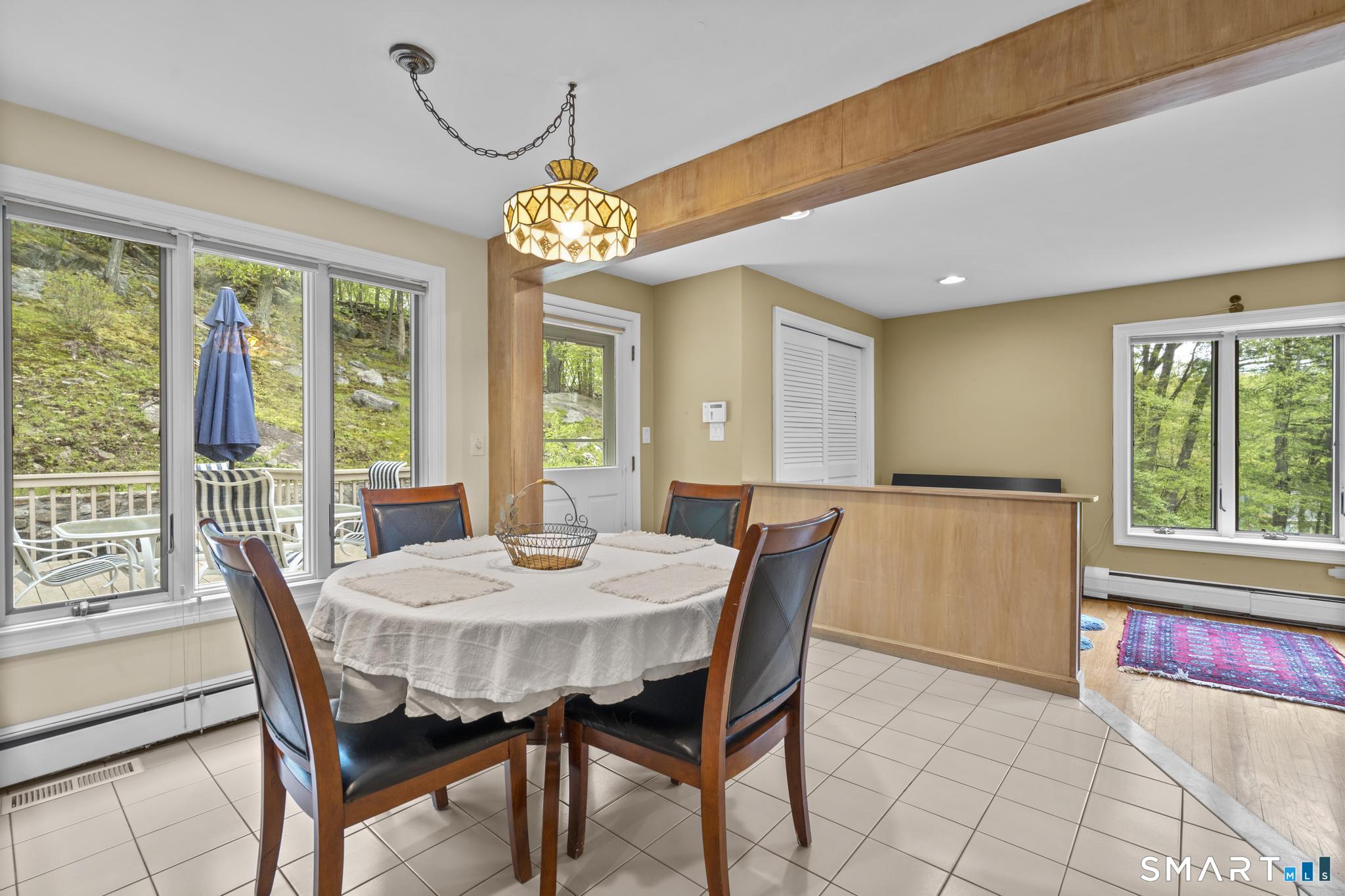 832 Quarter Mile Road Orange, CT 06477 - Photo 20 of 39 a view of a dining room with furniture a chandelier and large windows