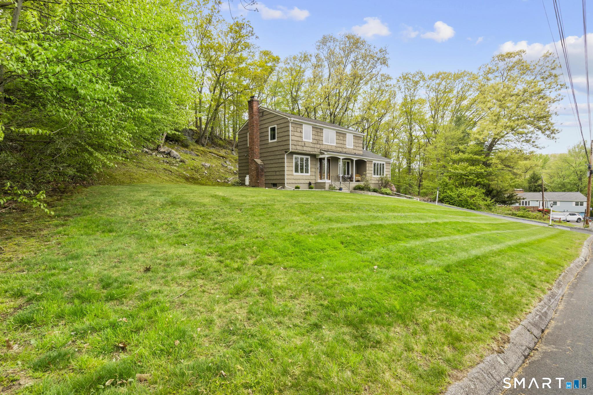 832 Quarter Mile Road Orange, CT 06477 - Photo 39 of 39 a view of a big yard in front of a brick house with a large tree
