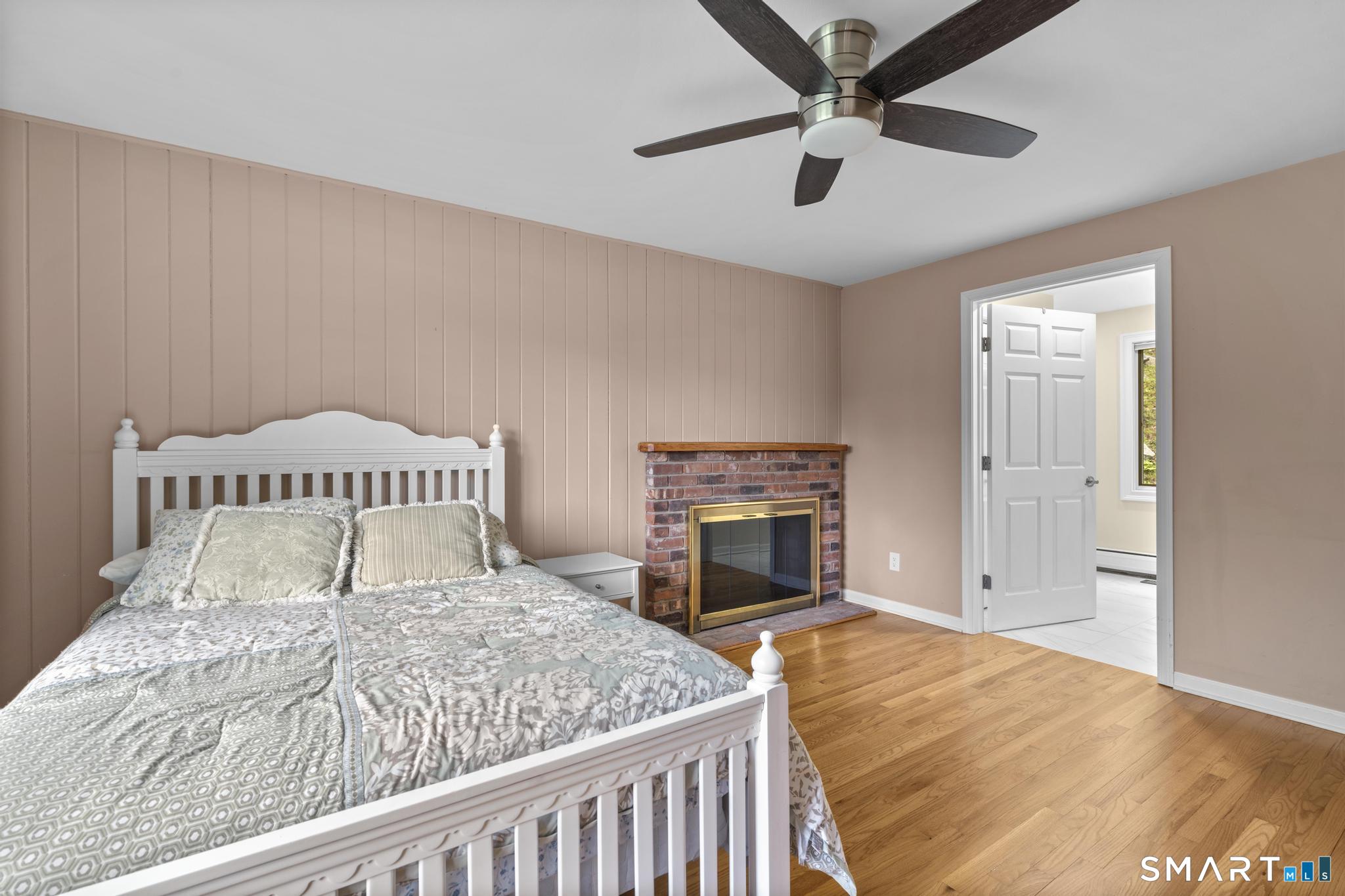 832 Quarter Mile Road Orange, CT 06477 - Photo 10 of 39 a bedroom with a large bed and a fireplace