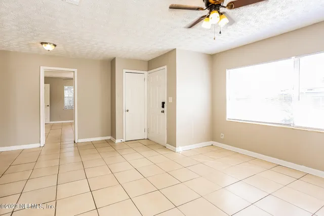 a view of an empty room and window with a chandelier fan