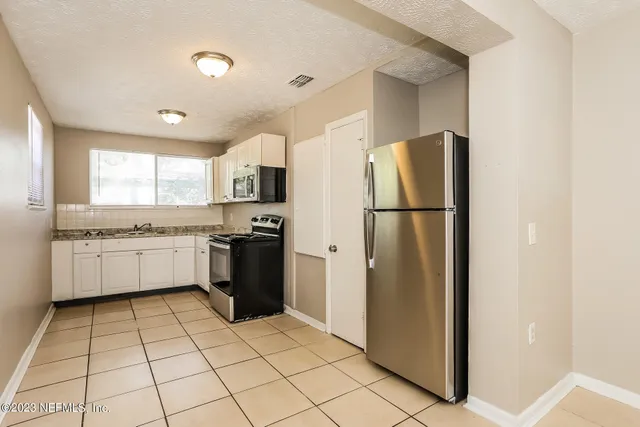 a kitchen with a refrigerator a stove top oven and cabinets