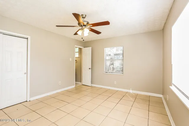a view of an empty room and window and a ceiling fan