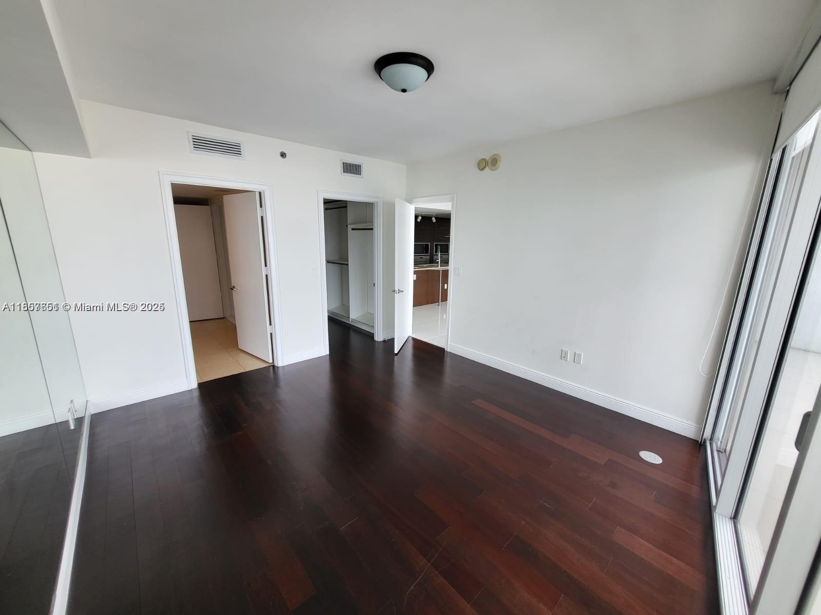 485 Brickell Avenue, Unit 4103 Miami, FL 33131 - Photo 8 of 13 an empty room with wooden floor and windows