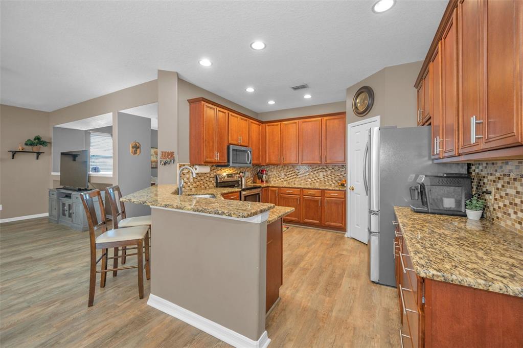 3619 Hatchbend Way Wesley Chapel, FL 33544 - Photo 15 of 86 a kitchen with stainless steel appliances granite countertop a stove top oven a sink dishwasher and a refrigerator with wooden floor