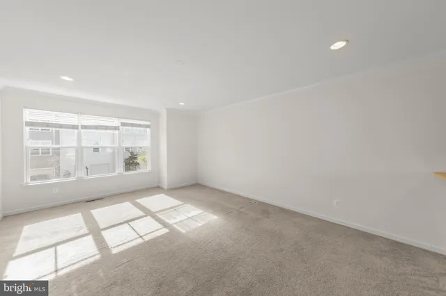 a view of an empty room with kitchen view and a window