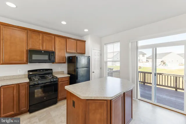 a kitchen with stainless steel appliances granite countertop a refrigerator a stove and a sink with wooden floor