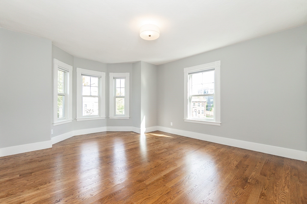 55 Phillips Street, Unit 55 Watertown, MA 02472 - Photo 8 of 15 an empty room with wooden floor and windows