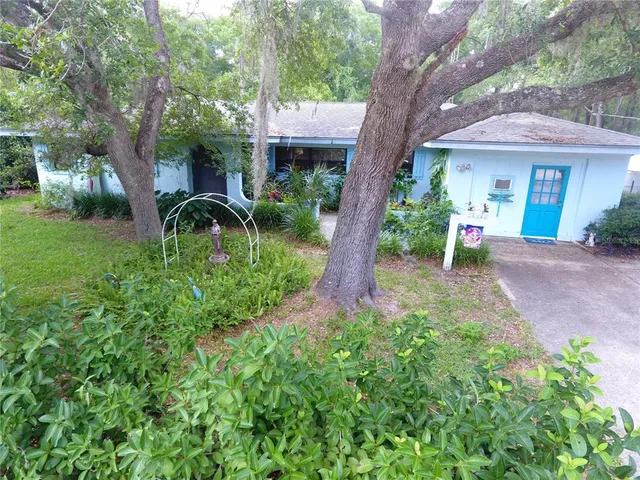 a view of a patio with table and chairs potted plants and large tree