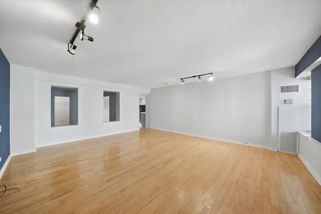 a view of an empty room with wooden floor and a ceiling fan