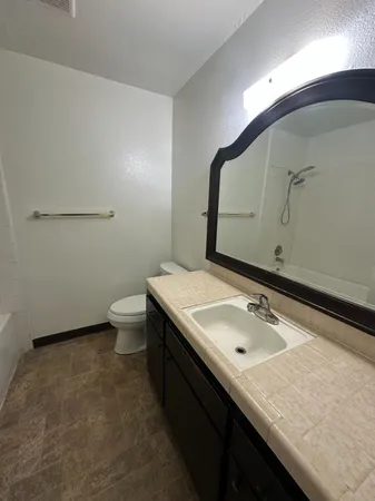 a bathroom with a granite countertop sink a toilet and mirror