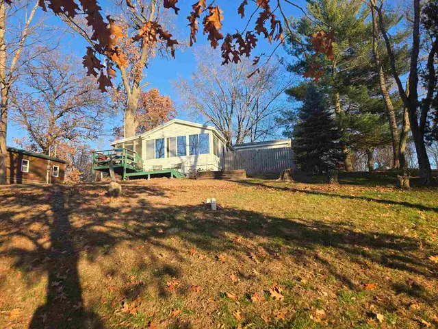 a front view of a house with a yard covered with snow and trees