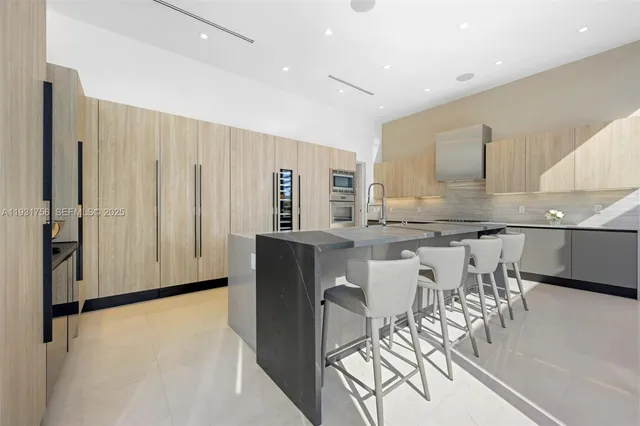 a large kitchen with kitchen island a large window a sink and stainless steel appliances