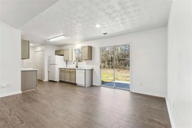 a view of a kitchen with a sink dishwasher cabinets and a large window