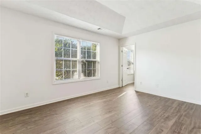 an empty room with wooden floor and windows