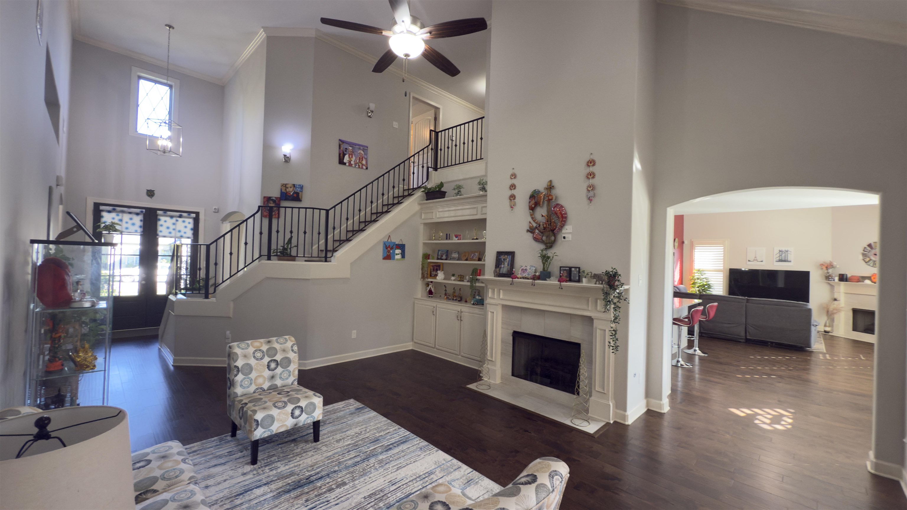 1217 Pilgrim Ridge Road Collierville, TN 38017 - Photo 7 of 33 Living room with a tile fireplace, a high ceiling, crown molding, stairs, and dark wood-style flooring