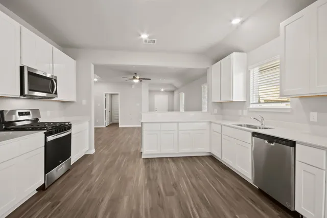 a kitchen with granite countertop a stove top oven a sink dishwasher and a refrigerator with wooden floor