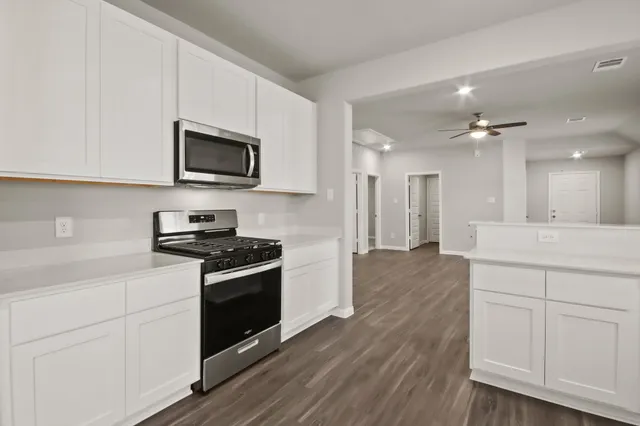 a kitchen with stainless steel appliances white cabinets a sink and a stove