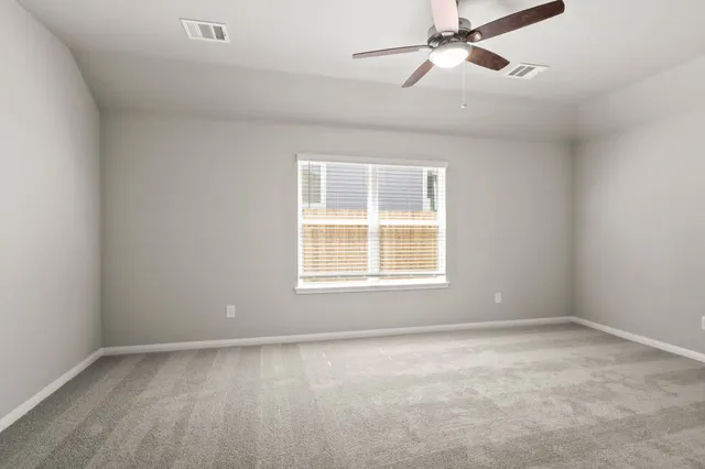 an empty room with a window and ceiling fan