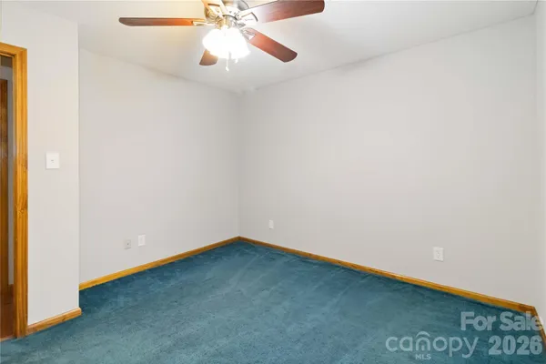an empty room with a ceiling fan and carpet