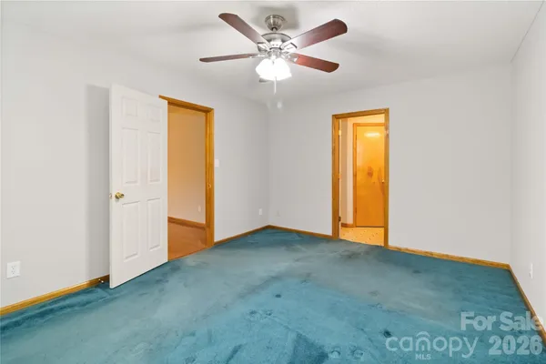 an empty room with closet and a ceiling fan