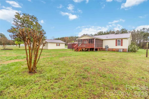 a view of a house with a big yard and large trees