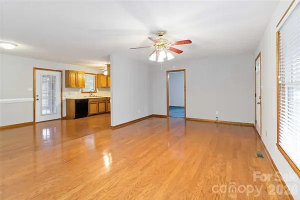 a view of an empty room with window and wooden floor
