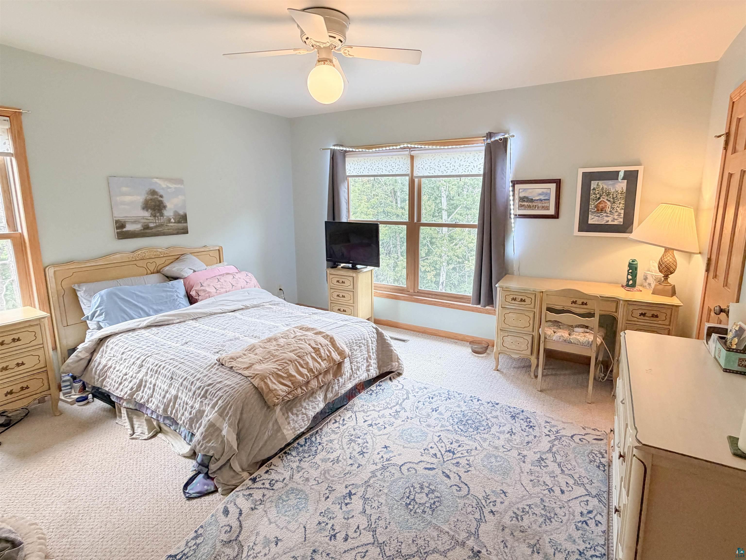 109 Prentice Heights Road, Unit 2 Ashland, WI 54806 - Photo 12 of 23 Recessed window with wood trim, ceiling fan light fixture, light neutral wall color, and light-colored carpeting